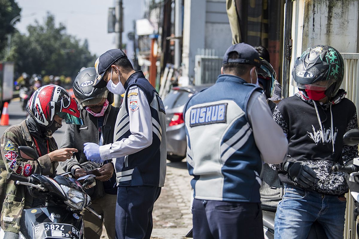 Petugas memeriksa kartu identitas saat Pembatasan Sosial Berskala Besar (PSBB) di Cimahi, Jawa Barat, Rabu (22/4/2020). Pemprov Jawa Barat mulai memberlakukan (PSBB) Kota Bandung, Kota Cimahi, Kabupaten Bandung, Kabupaten Bandung Barat, dan Kabupaten Sumedang dalam rangka percepatan penanganan COVID-19 selama 14 hari dimulai pada 22 April hingga 5 Mei 2020.