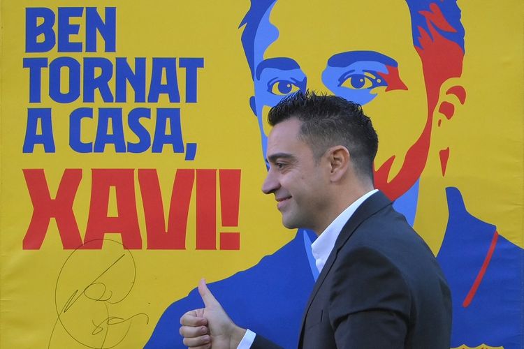 Pelatih baru Barcelona Xavi Hernandez berpose di sebelah poster bertuliskan Selamat Datang Kembali pada upacara presentasinya di Stadion Camp Nou di Barcelona pada 8 November 2021.
