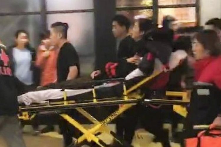 Petugas medis membawa korban yang terluka akibat penyerangan pria menggunakan pisau di sebuah mall di Beijing, Minggu (11/2/2018).