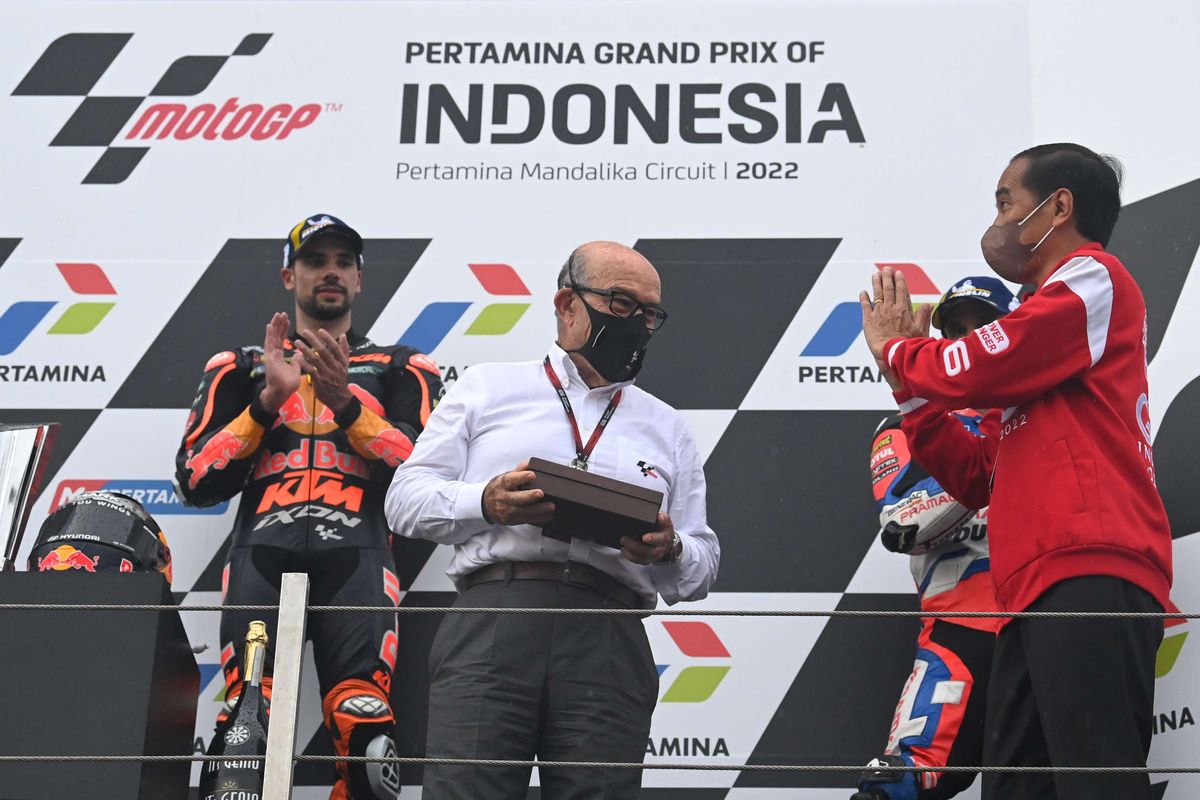 Presiden Joko Widodo (kanan) memberikan cenderamata kepada CEO Dorna Sports Carmelo Ezpeleta (kedua kiri) disaksikan pembalap Red Bull KTM Factory Racing Miguel Oliveira (kiri) di podium seusai balapan MotoGP seri Pertamina Grand Prix of Indonesia di Pertamina Mandalika International Street Circuit, Lombok Tengah, NTB, Minggu (20/3/2022).