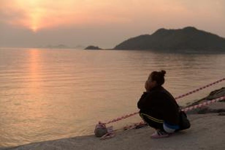 Seorang keluarga penumpang kapal Sewol, feri yang tenggelam di Korea Selatan pada Rabu (16/4/2014), duduk di tepi pantai di Pelabuhan Jindo, Rabu (23/4/2014). Harapan untuk menemukan lagi korban selamat semakin menepis.  