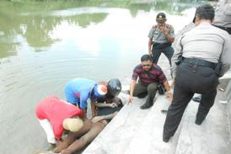 Warga bersama polisi saat memindahkan jenasah Hendro Dwi Jatmiko ( 22 ), warga Kampung Brumbungan , Kelurahan Gabahan , Kecamatan Semarang Tengah,yang ditemukan tewas tenggelam di Kali Jajar , Demak, Jumat ( 23/5/2014). 