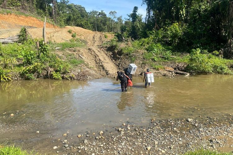 Anggota Kepolisian Polres Keerom, saat membantu memikul logistik pemilu berjalan kaki selama 12 jam ke TPS di Kampung Milki, Distrik Towe, Kabupaten Keerom, Papua, Rabu (12/4/2024).