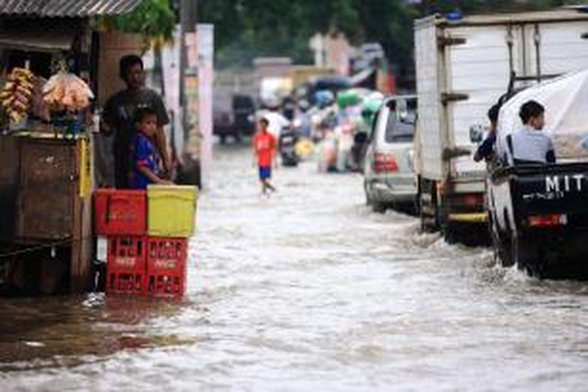 Pedagang kaki lima mengamati banjir luapan Kali Angke yang menggenangi Jalan Hasyim Ashari, Ciledug, Tangerang, Rabu (29/1/2014). Hujan deras yang turun sejak kemarin malam kembali menimbulkan banjir di sejumlah titik di Jakarta dan sekitarnya. KOMPAS/TOTOK WIJAYANTO