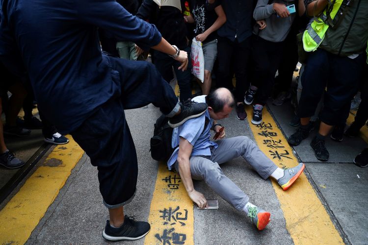 Seorang pria dihajar hingga babak belur oleh demonstran penentang pemerintah dalam aksi protes di Central, Hong Kong, pada 14 November 2019.