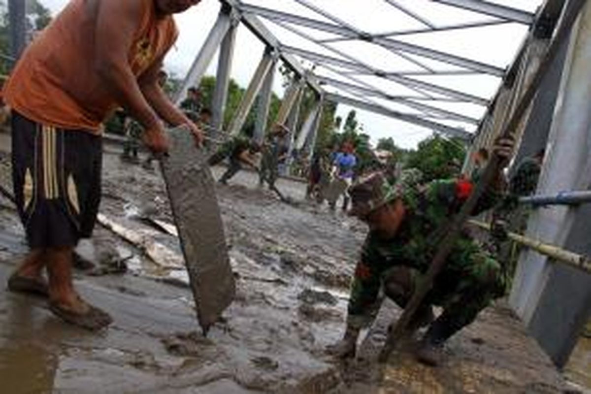 Anggota TNI dari Denzipur membantu warha menyingkirkan lumpur akibat banjir yang menerjang Kota Manado.