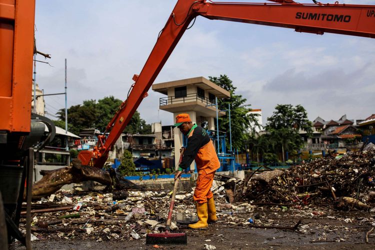 Petugas kebersihan DKI Jakarta mengangkut sampah yang terbawa arus menggunakan alat berat di Pintu Air Manggarai, Jakarta, Minggu (17/2/2019). Kenaikan muka air di Pintu Air Manggarai diakibatkan oleh hujan yang mengguyur Jakarta dan sekitarnya mulai Sabtu (16/2/2019) malam selama beberapa jam.