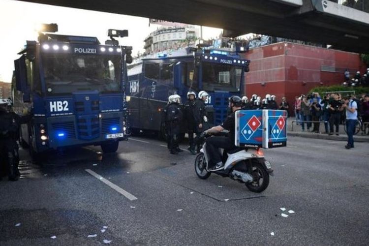 Sebelum menembus kerumunan pengunjung rasa sang pengantar pizza harus menembus barikade polisi yang mengamankan KTT G20 di Hamburg, Jerman.