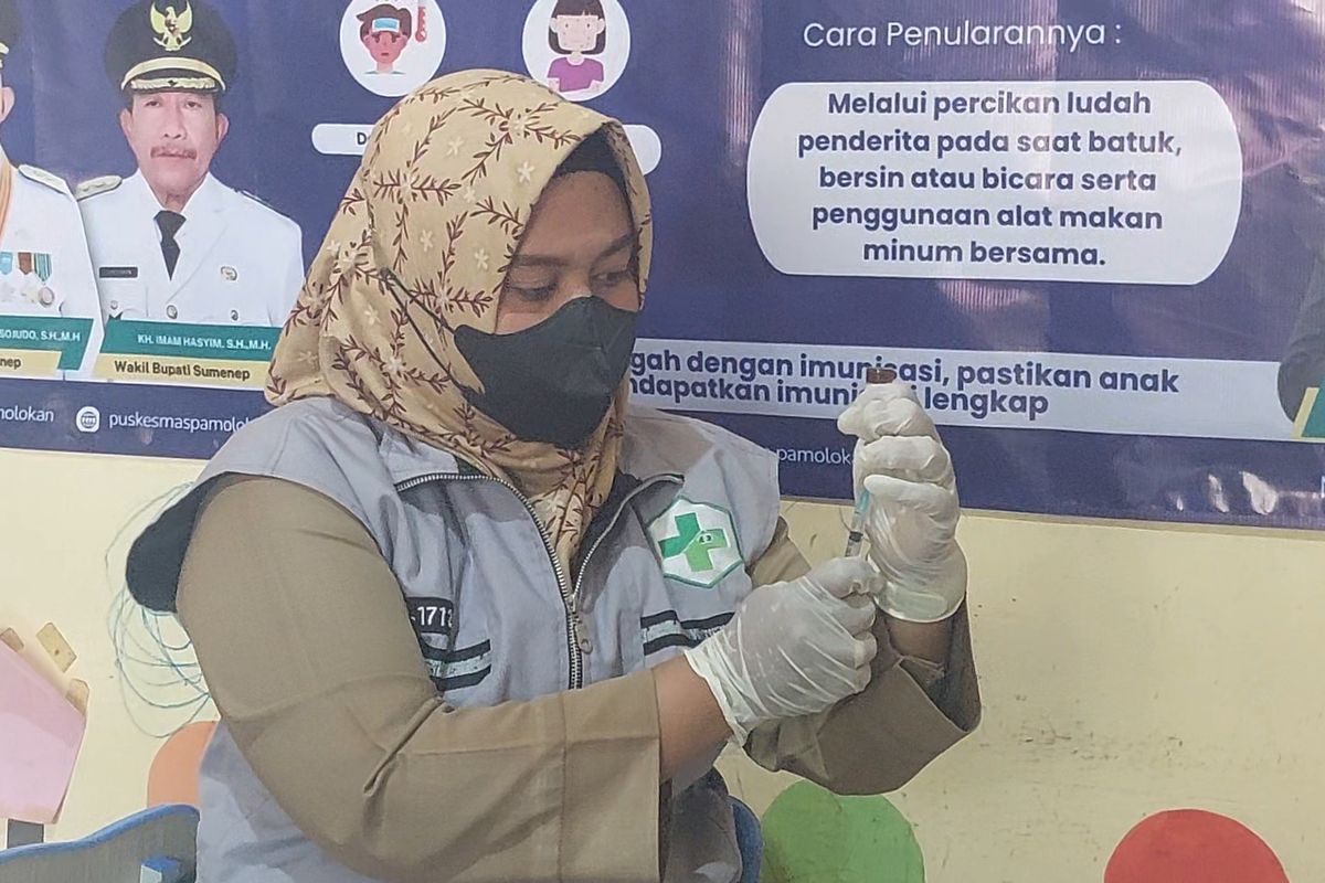 Petugas menyiapkan vaksin untuk disuntikkan kepada anak yang menjadinsasaran vaksinasi. 