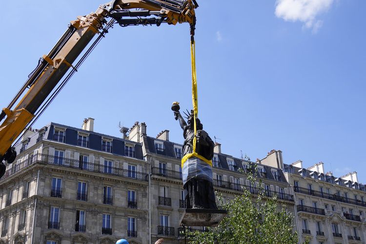 Para pekerja mengamankan pemindahan Liberty Enlightening the World karya Frederic Auguste Bartholdi, replika mini Patung Liberty rancangan Prancis, di Paris, Senin, 7 Juni 2021. 