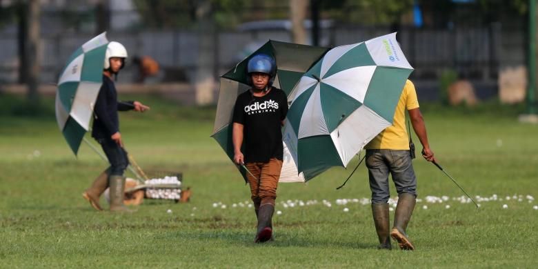 Beberapa pekerja mengumpulkan bola golf di Senayan Golf Driving Range, Jakarta, Rabu (16/7/2014). Demi keselamatan saat bekerja, mereka menggunakan helm dan payung agar terhindar dari pukulan bola. KOMPAS/TOTOK WIJAYANTO