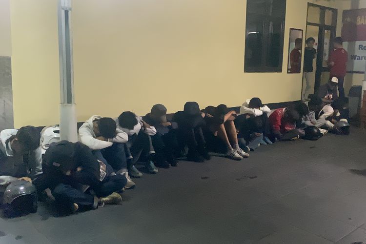 Sebanyak 13 orang supertor Persija Jakarta yang tengah berada di Polsek Warudoyong Kota Sukabumi tertunduk malu, mereka diamankan dari buntuk aksi pengrusakan pagar rumah milik warga di Jalan Pajagalan, Kota Sukabumi, Senin (23/9/2024). 