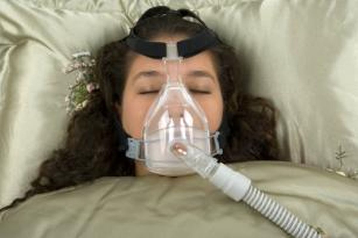 Ilustrasi  perempuan menggunakan alat terapi mendengkur (CPAP)