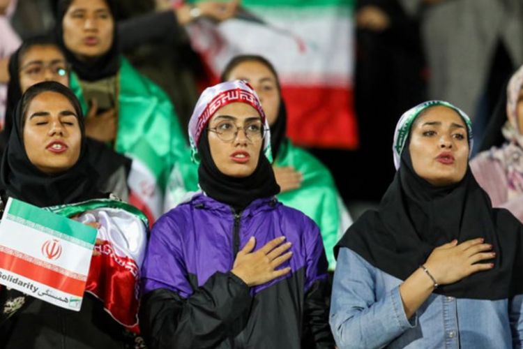 Fans perempuan Iran menyanyikan lagu kebangsaan saat tim nasional Iran beruji coba dengan Bolivia di Stadion Azadi Teheran, Selasa (16/10/2018).