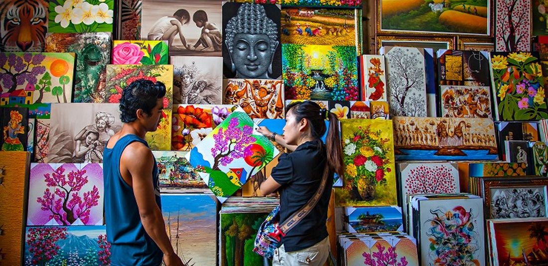 Seorang penjual lukisan dan pembeli di Pasar Seni Sukawati, Bali.