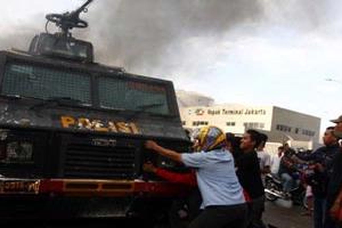 Massa berusaha menggulingkan kendaraan water canon milik polisi saat bentrokan dengan Satpol PP dalam upaya pembongkaran kompleks makam Mbah Priok di Koja, Jakarta Utara, Rabu (14/4/2010). Bentrokan mengakibatkan sedikitnya seratus orang terluka dan belasan kendaraan roda dua dan empat dibakar massa.