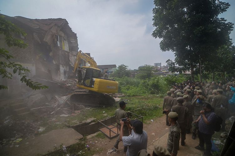 Petugas mengoperasikan alat berat untuk menghancurkan rumah saat penggusuran permukiman Tamansari di Bandung, Jawa Barat, Kamis (12/12/2019). Upaya penggusuran tersebut berakhir ricuh setelah Satpol PP memaksa warga dan aktivis mahasiswa untuk mengosongkan tempat tinggalnya di lahan sengketa di mana proses sidang sengketa lahan masih berlangsung di PTUN Bandung.