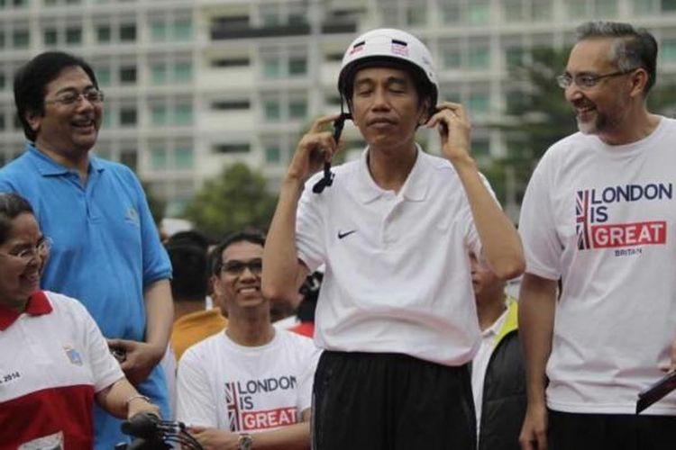 Presiden Joko Widodo mengenakan helm dan disaksikan oleh Duta Besar Inggris untuk Indonesia Moazzam Malik di kawasan Bundaran Hotel Indonesia, Jakarta, Minggu (30/11/2014). Pada acara ini Pemerintah Kota London menyumbangkan 12 unit sepeda ke Pemerintah Provinsi DKI Jakarta. 