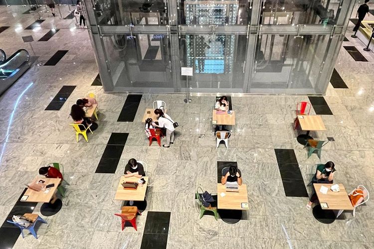 Foto pengunjung yang menggunakan meja yang berjarak jauh satu sama lain untuk melaksanakan aktivitasnya di area terbuka Tanjong Pagar Centre, Singapura, Kamis malam (1/7/2021)