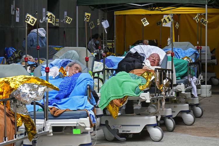 Pasien berbaring di ranjang rumah sakit saat mereka menunggu di ruang tunggu sementara di luar Caritas Medical Center di Hong Kong Rabu, 16 Februari 2022. 