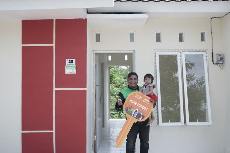 Donny Eko Prasetyo, mitra driver Gojek, beserta keluarganya saat menerima secara simbolis kunci rumah Program KPR Subsidi. 
