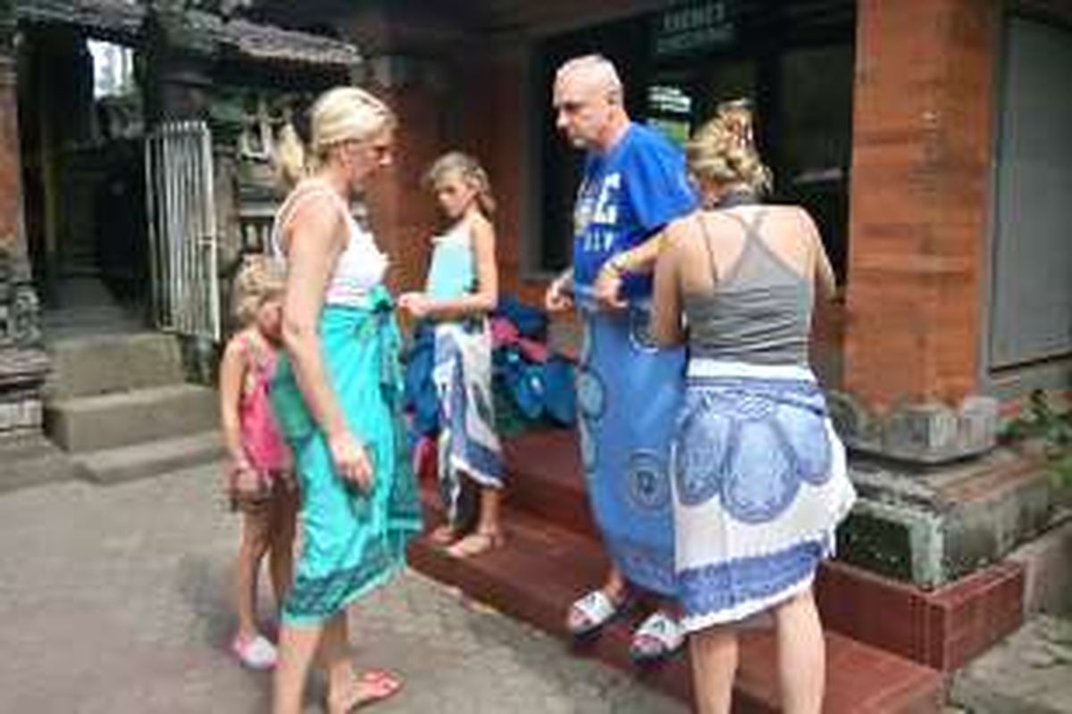 Wisatawan asing mengenakan kain yang disediakan petugas di Goa Gajah, Kabupaten Gianyar, Bali, Jumat (1/4/2016). 