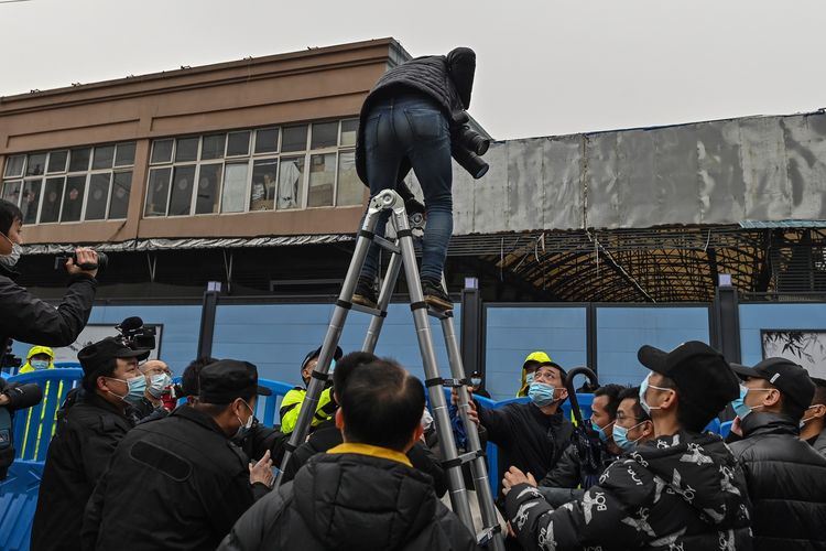 Petugas keamanan menggoyang tangga yang dipakai seorang fotografer untuk memotret tim WHO di pasar seafood Huanan di Wuhan, China, pada Minggu (31/1/2021) dan memintanya turun.