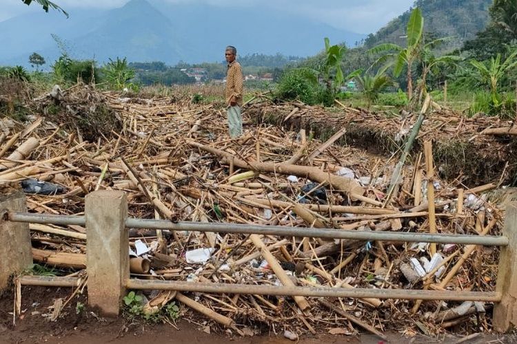 Seorang warga berdiri di tumpukan sampah yang menyumbat aliran Sungai Cibuyutan, Kecamatan Banyuresmi, Kabupaten Garut, Jawa Barat, Sabtu (20/11/2021). 