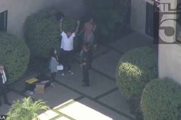 Penyanyi Chris Brown (berkaus putih) bersama polisi dan pengacaranya (sedang menelepon) berada di luar rumah selama polisi menggeledah rumahnya di Los Angeles, Selasa (30/8/2016).