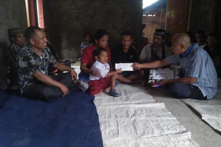 Rivaldus Eman Jau (7) bersama orang tuanya dan warga kampung Wolosambi, Desa Komba, Kecamatan Kota Komba, Manggarai Timur, NTT, Jumat, (23/12/2022) menerima donasi dari pembaca KOMPAS.com di kediamannya. (KOMPAS.com/MARKUS MAKUR)