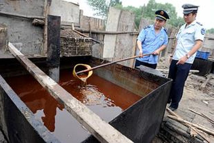 Seorang polisi China memeriksa wadah penampungan minyak goreng bekas atau 