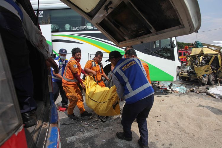 Petugas mengevakuasi jenazah korban kecelakaan bus pariwisata dengan truk di Tol Dupak - Tanjung Perak Surabaya, Jawa Timur, Sabtu (5/3/2022). Kecelakaan antara bus pariwisata bernopol D 7610 AT yang memuat rombongan peziarah dengan truk 'Colt Diesel' nomor polisi W 9948 Z itu diduga disebabkan salah satu penumpang bus merebut kendali kemudi dari sopir bus dan menabrak truk 'Colt Diesel' dari arah berlawanan. Dalam kecelakaan itu sopir truk dan kernetnya meninggal dunia di lokasi kecelakaan.