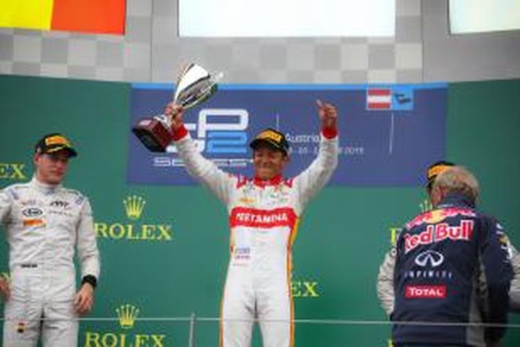 Pebalap Campos Racing asal Indonesia, Rio Haryanto (tengah), mengangkat trofi di atas podium Sirkuit Red Bull, Spielberg, setelah memenangi sprint race GP2 Austria, Minggu (21/6/2015). Stoffel Vandoorne (kiri) finis kedua dan Nobuharu Matsushita finis ketiga.