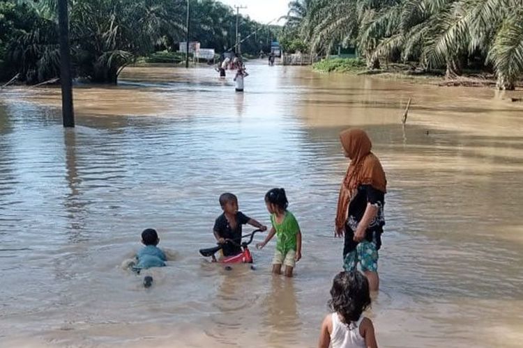 Sejumlah anak bermain di genangan banjir di Indra Makmur, Kabupaten Aceh Timur, Jumat (19/11/2021). 