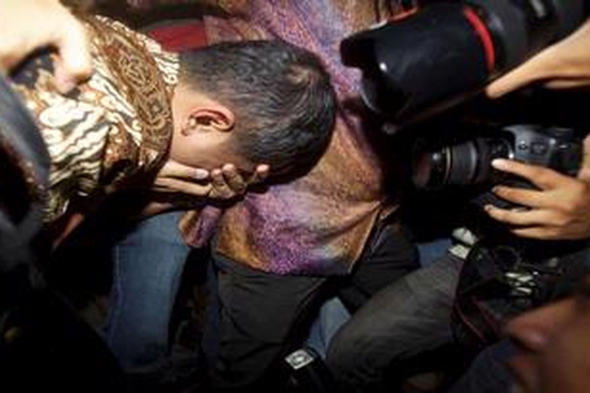Mantan pegawai Ditjen Pajak, Dhana Widyatmika menutup wajah saat keluar dari ruang pemeriksaan Tindak Pidana Khusus, Kejaksaan Agung, Jakarta, Kamis (1/3/2012). Tersangka kasus dugaan korupsi dan pencucian uang tersebut diperiksa lebih kurang 10 jam terkait rekening gendut yang dilaporkan Pusat Pelaporan dan Analisis Transaksi Keuangan (PPATK).
