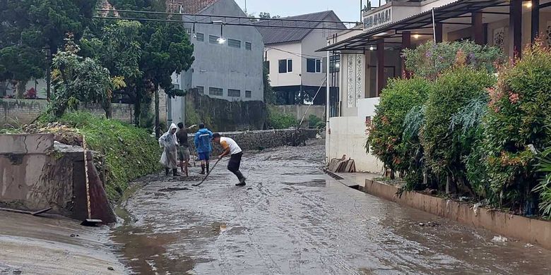 Warga di Kompleks Graha Indah membersihkan sisa material lumpur usai diterjang banjir, Senin (20/6/2022).