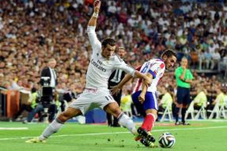 Bintang Real Madrid, Gareth Bale, berebut bola dengan gelandang Atletico Madrid, Koke pada pertandingan leg pertama Piala Super Spanyol di Santiago Bernabeu, Selasa atau Rabu (20/8/2014) pagi WIB. 