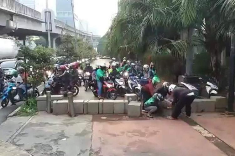 Pengendara motor bahu-membahu mengangkut beton di trotoar depan TPU Menteng Pulo, Jalan Casablanca, Setiabudi, bisa lewat.