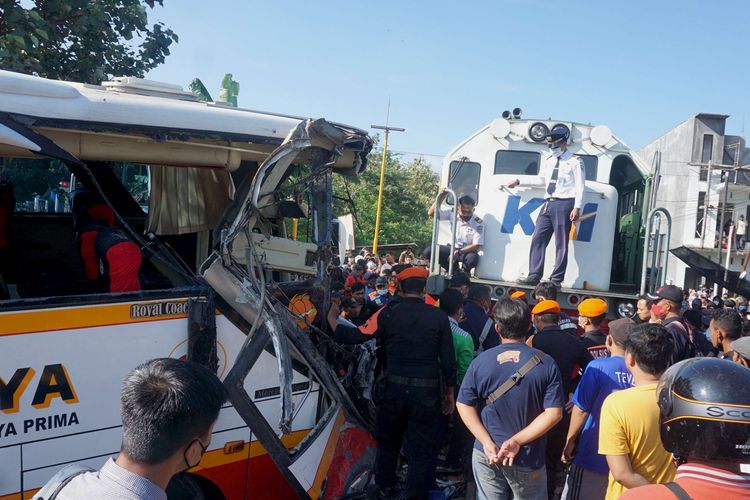 Warga melihat proses evakuasi lokomotif KA Rapih Dhoho yang menabrak bus pariwisata PO Harapan Jaya di perlintasan kereta api tanpa palang pintu di Desa Ketanon, Tulungagung, Jawa Timur, Minggu (27/2/2022). Kecelakaan yang terjadi sekitar pukul 05.00 WIB itu menyebabkan lima dari 43 penumpang termasuk awak bus meninggal dunia dan 14 lainnya luka-luka dan harus dilarikan ke RSUD dr. Iskak Tulungagung untuk mendapat pertolongan kedaruratan medis.