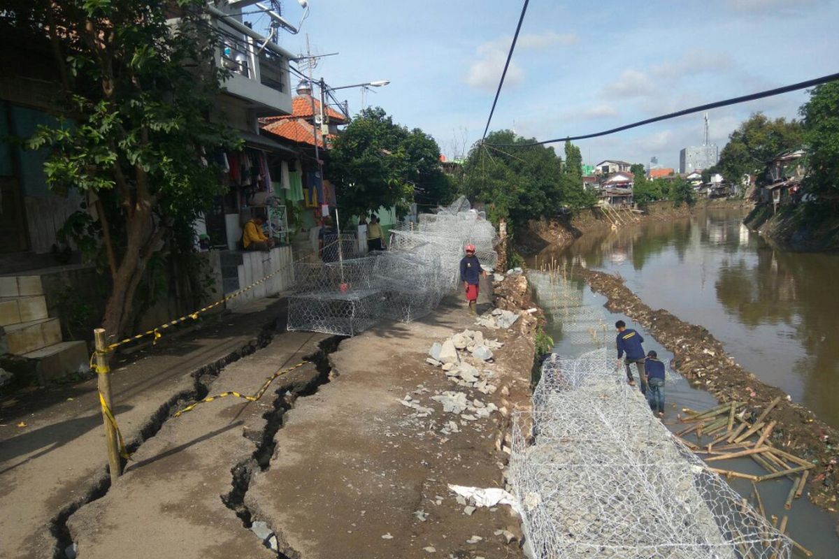 Petugas sedang memasang beronjong di pinggir kali yang longsor di kawasan Berlan, Matraman, Jakarta, Senin (19/2/2018).