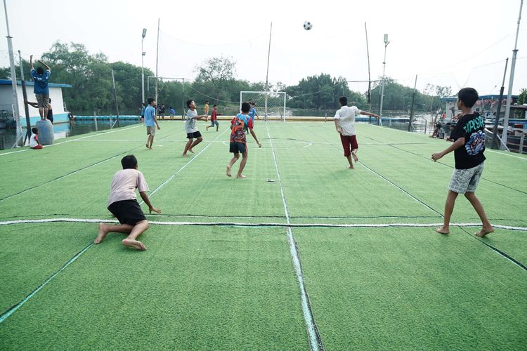 Anak-anak bermain bola di Lapangan Futsal Apung, Muara Angke, Jakarta Utara, Jumat (27/6/2025). Lapangan Apung tersebut didirikan oleh Kementerian Pertahanan yang bekerja sama dengan Universitas Pertahanan pada tahun 2024.
