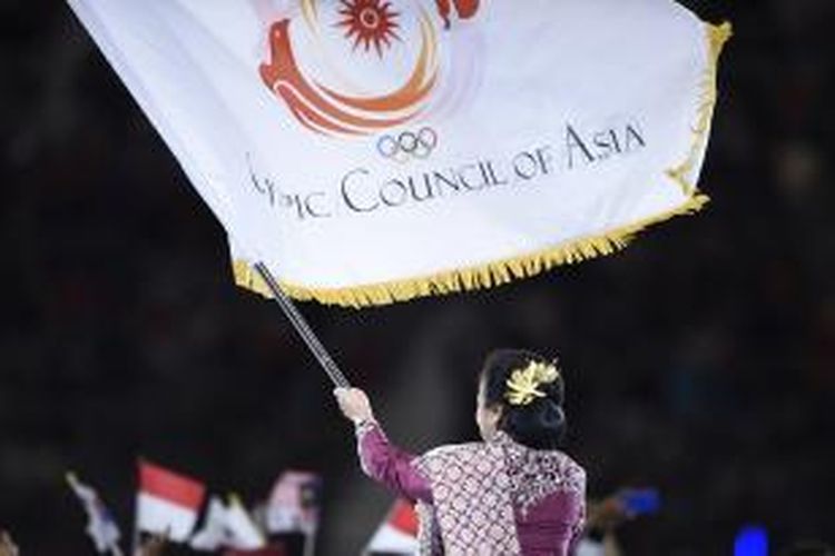 Ketua Komite Olahraga Indonesia, Rita Subowo, mengibarkan bendera Dewan Olimpiade Asia (OCA), Sabtu (4/10/2014), yang baru saja dia terima sebagai penanda Indonesia menjadi tuan rumah Asian Games XVIII pada 2018. Penyerahan simbol tuan rumah Asian Games ini merupakan bagian dari upacara penutupan Asian Games XVII di Korea Selatan