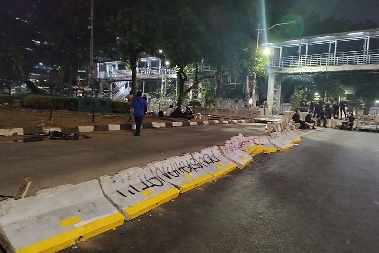 Beton pembatas busway jatuh dan dicoret-coret saat demo evaluasi sembilan tahun pemerintahan Presiden Joko Widodo di Patung Kuda, Gambir, Jakarta Pusat, Jumat (20/10/2023). (KOMPAS.com/XENA OLIVIA)
