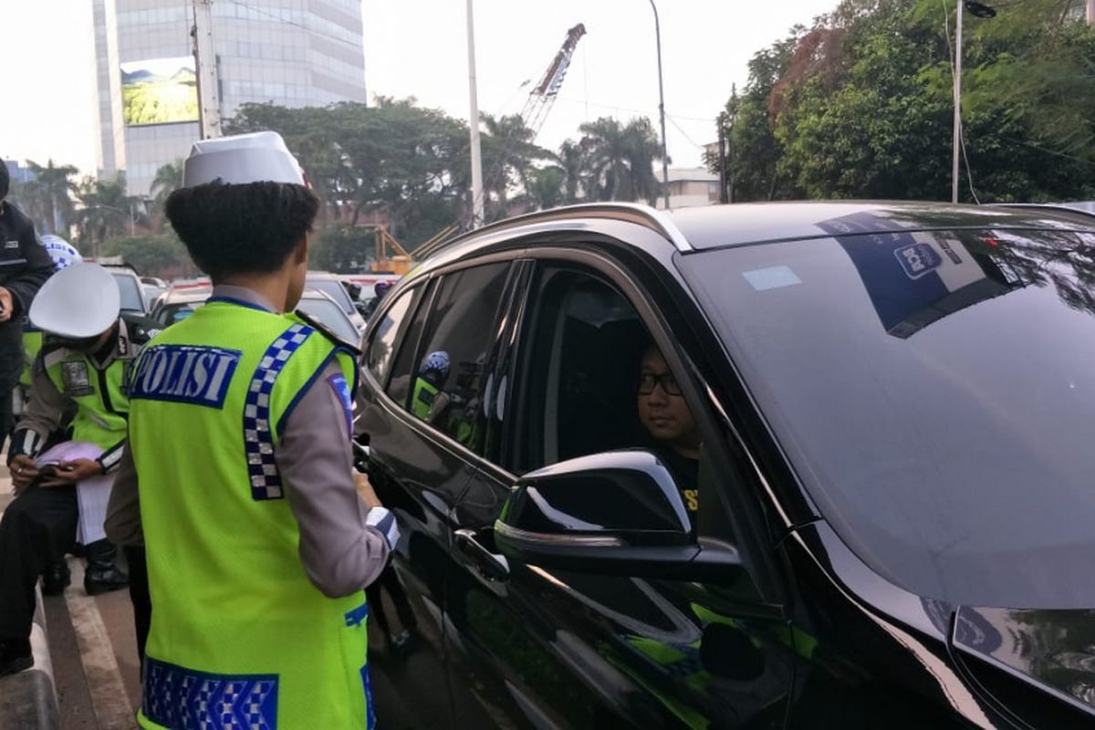 Polisi menilang pengendara mobil berpelat genap di Jalan Gatot Subroto, simpang Pancoran, Jakarta Selatan, Rabu (1/8/2018).