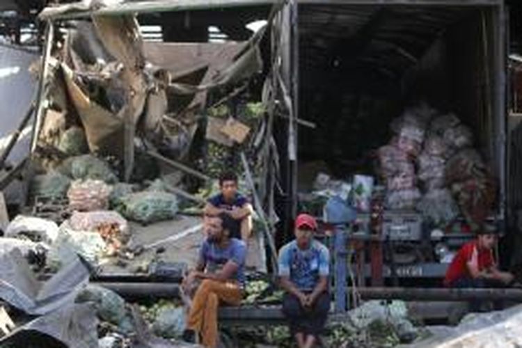 Beberapa warga Baghdad hanya bisa termangu di dekat puing-puing kendaraan yang hancur akibat bom truk di sebuah pasar di kota itu, Kamis (13/8/2015). Insiden itu menewaskan 38 orang dan melukai 80 orang lainnya.