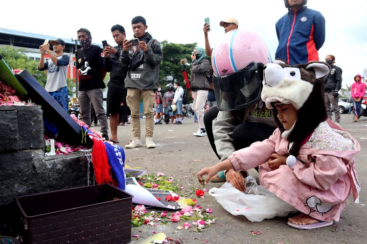 Ajeng dan anaknya menabur bunga dan berdoa di monumen Singo Tegar tepat di hari kedua pasca tragedi yang terjadi pada pekan ke-11 Liga 1 2022-2023 seusai pertandingan bertajuk Derbi Jawa Timur, Arema FC melawan Persebaya Surabaya di Stadion Kanjuruhan Kepanjen, Kabupaten Malang, Senin (3/10/2022) siang.