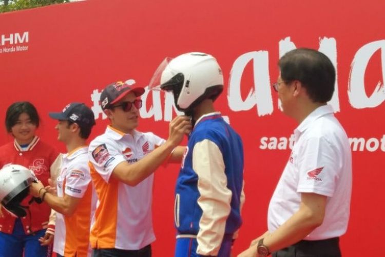 Pebalap Repsol Honda Team, Marc Marquez, memasangkan helm kepada anak SMA TSM Honda, di Astra Biz Center, BSD, Tangerang, Selasa (17/10/2017).