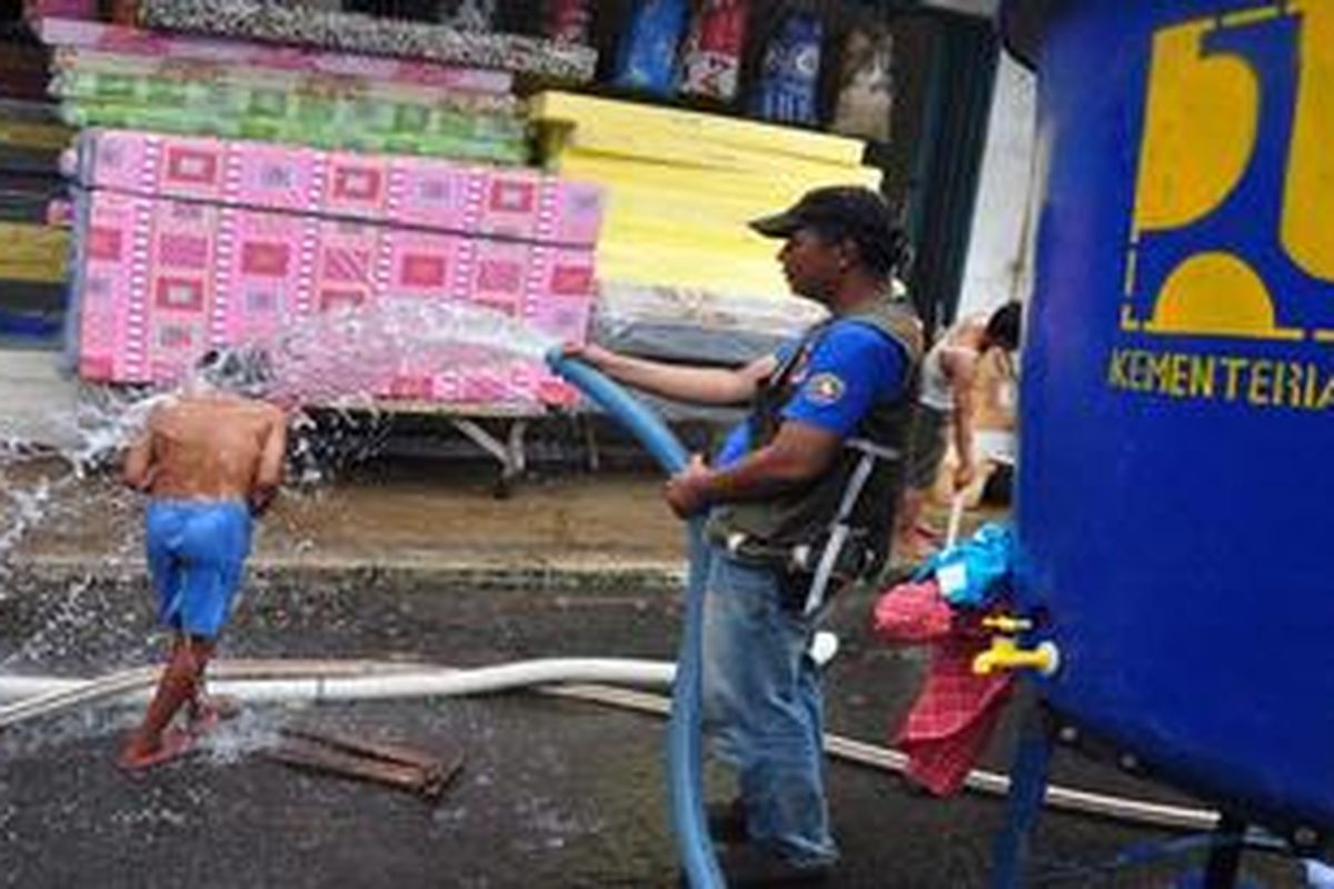 Seorang bocah mandi melalui aliran instalasi penjernih air yang merupakan bantuan untuk pengungsi korban banjir Kampung Pulo di Jatinegara Barat, Jakarta Timur, Senin (21/1/2013). Mobiil yang merupakan penyulingan air sungai menjadi air bersih ini digunakan untuk warga mandi, minum, masak dan keperluan lainnya. Sumber air yang digunakan melalui aliran sungai Ciliwung. KOMPAS IMAGES/ANDREAN KRISTIANTO