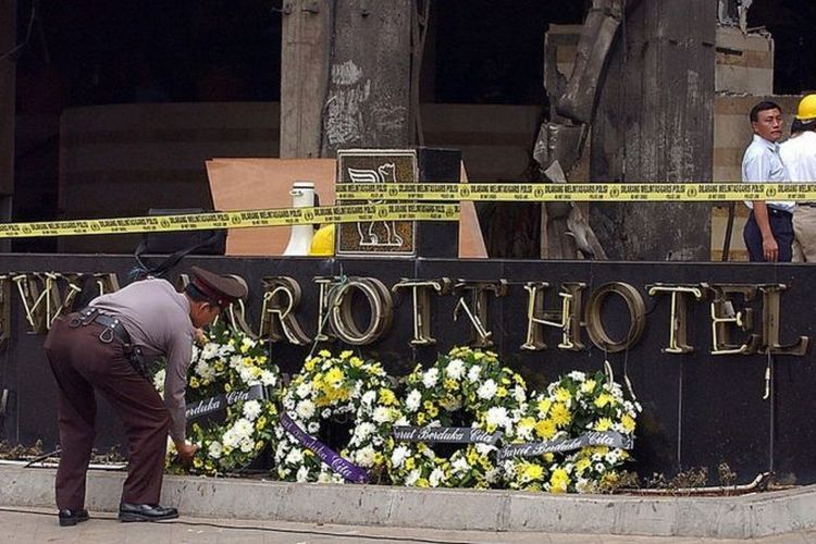 Seorang petugas polisi merapikan karangan bunga di depan Hotel JW Marriott, Jakarta, setelah ledakan bom 5 Agustus 2003.