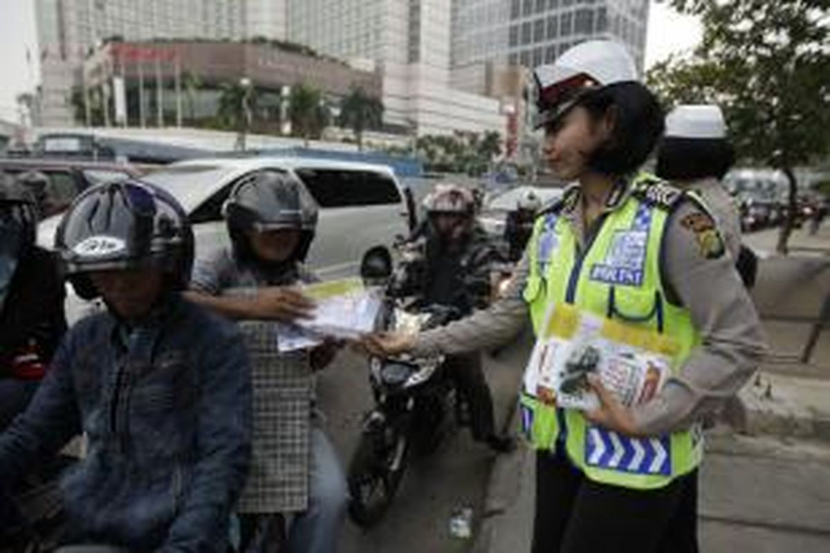 Polisi membagikan takjil sekaligus peta jalur mudik kepada pengguna jalan, di Jalan MH Thamrin, Jakarta, Jumat (18/7/2014). Petugas juga menghimbau agar calon pemudik lebaran tidak menggunakan motor saat mudik nanti, karena pemudi yang menggunakan motor rentan mengalami kecelakaan.